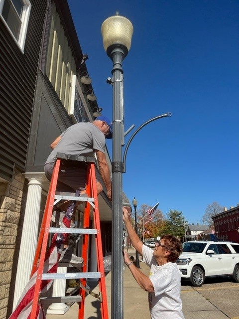 Mayor Stanley and Becky Hansen install lights on a light pole